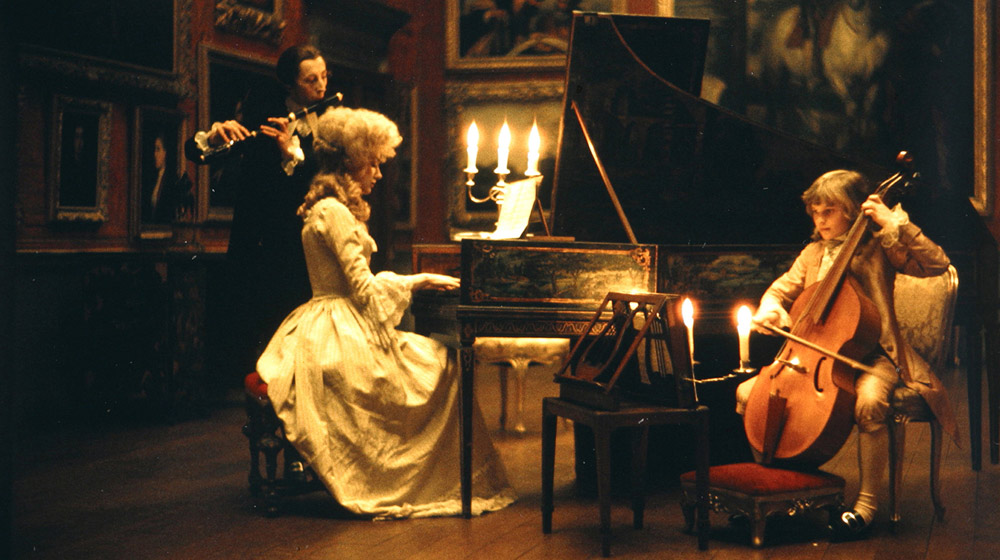 Lady Lyndon (Marisa Berenson) plays the piano with her son, Bryan Patrick Lyndon (David Morley), with tutor Reverend Samuel Runt (Murray Melvin), in the background Film Still © Warner Bros. Entertainment Inc.